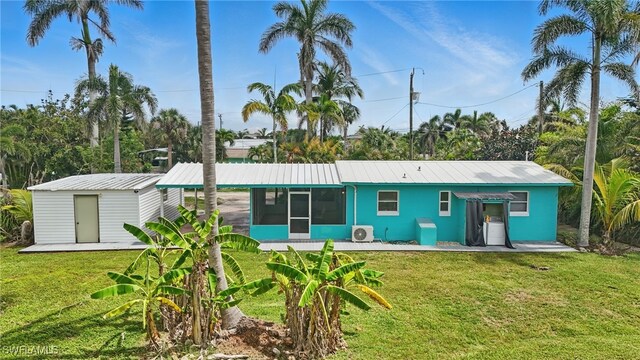 7434 Cares Away Park Cir, Bokeelia, FL 33922 - back of property featuring a sunroom, a lawn, a metal roof, and a storage unit