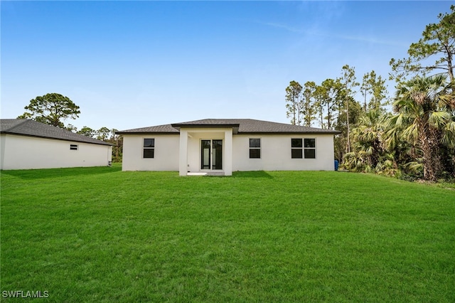 2704 22nd St W, Lehigh Acres, FL 33971 - back of house featuring a lawn and stucco siding