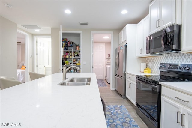 14727 Edgewater Cir, Naples, FL 34114 - kitchen featuring electric range, freestanding refrigerator, light countertops, white cabinets, and decorative backsplash