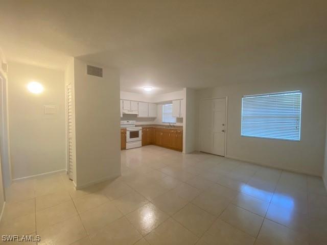 3325 Airport Pulling Rd N Unit F1, Naples, FL 34105 - kitchen featuring electric stove, white cabinets, and light tile patterned floors
