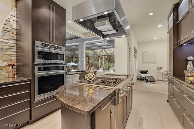 364 Logan Blvd S, Naples, FL 34119 - kitchen with ventilation hood, a kitchen island, dark stone counters, recessed lighting, and dark brown cabinetry