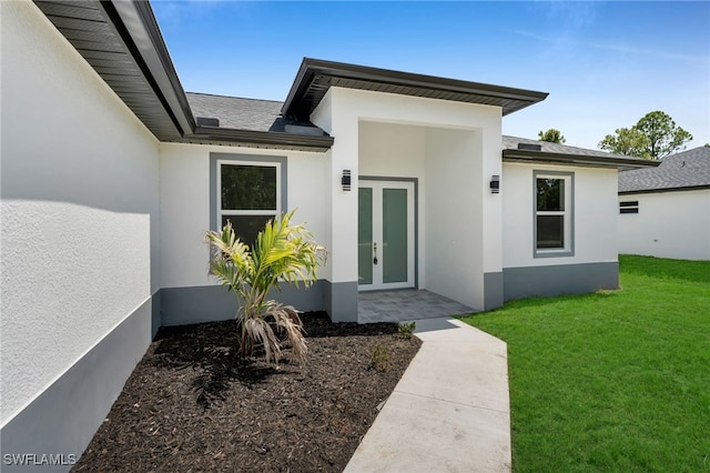 2605 28th St W, Lehigh Acres, FL 33971 - property entrance featuring french doors, stucco siding, a lawn, and a shingled roof