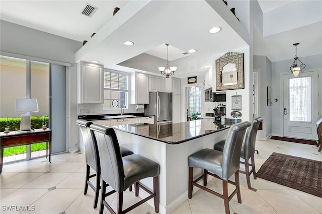 3008 Ellice Way, Naples, FL 34119 - kitchen featuring stainless steel appliances, dark countertops, a breakfast bar, pendant lighting, and a chandelier