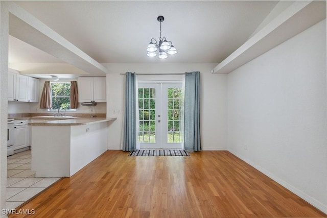 3210 2nd Ave SE, Naples, FL 34117 - kitchen with white cabinets, a peninsula, light wood-style flooring, a chandelier, and light countertops