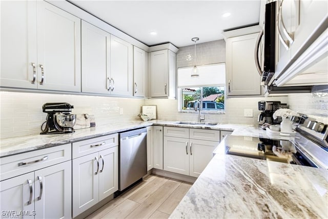 7208 Saint Anns Ct, Fort Myers, FL 33908 - kitchen featuring appliances with stainless steel finishes, decorative backsplash, light wood finished floors, pendant lighting, and light stone countertops