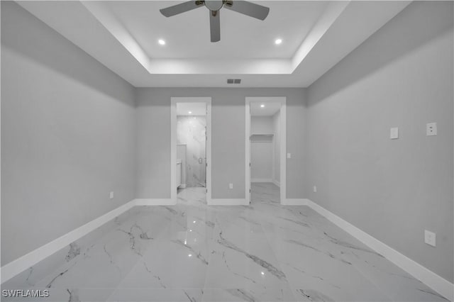 3103 Karen Ave S, Lehigh Acres, FL 33976 - unfurnished bedroom featuring a tray ceiling, a walk in closet, recessed lighting, light marble finish flooring, and ensuite bath
