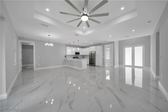 3103 Karen Ave S, Lehigh Acres, FL 33976 - unfurnished living room with a raised ceiling, a chandelier, recessed lighting, a ceiling fan, and french doors