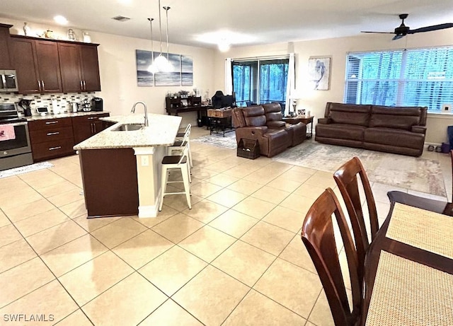 20608 Long Pond Rd, North Fort Myers, FL 33917 - kitchen featuring stainless steel range with electric stovetop, open floor plan, light tile patterned floors, a breakfast bar, and dark brown cabinetry