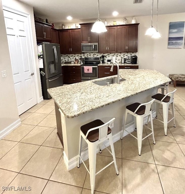 20608 Long Pond Rd, North Fort Myers, FL 33917 - kitchen with appliances with stainless steel finishes, light tile patterned floors, backsplash, and a kitchen breakfast bar