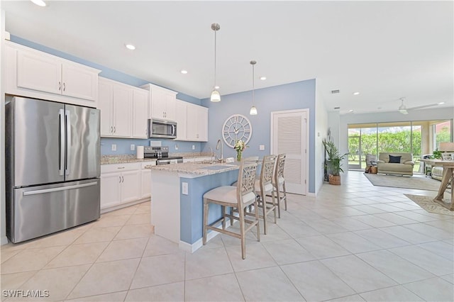 4209 Bloomfield St, Fort Myers, FL 33916 - kitchen featuring appliances with stainless steel finishes, a kitchen bar, white cabinets, light tile patterned flooring, and a center island with sink