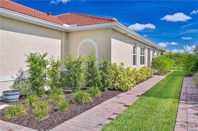 4209 Bloomfield St, Fort Myers, FL 33916 - view of side of home with stucco siding, a tiled roof, and a yard