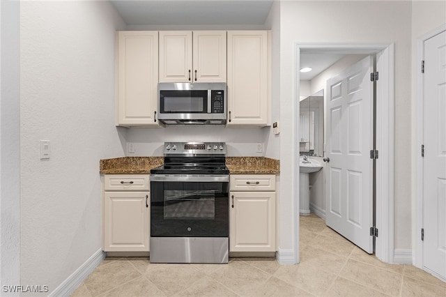 16142 Via Solera Cir Unit 103, Fort Myers, FL 33908 - kitchen with stainless steel appliances, light tile patterned floors, dark stone counters, and white cabinets