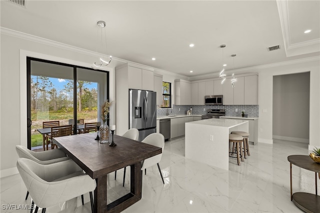 3587 18th Ave SE, Naples, FL 34117 - kitchen featuring stainless steel appliances, a kitchen island, crown molding, light countertops, and a kitchen breakfast bar