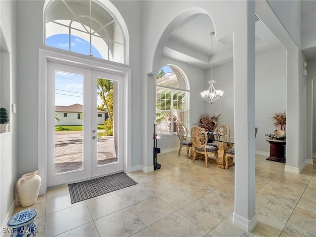 2705 SW 30th Ter, Cape Coral, FL 33914 - foyer entrance featuring french doors, a chandelier, a towering ceiling, a tray ceiling, and light tile patterned floors