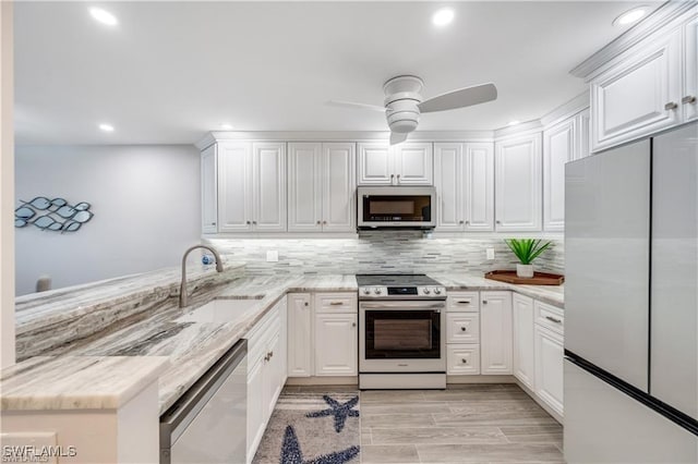 26000 Hickory Blvd Unit 205, Bonita Springs, FL 34134 - kitchen with stainless steel appliances, a ceiling fan, white cabinets, a peninsula, and backsplash