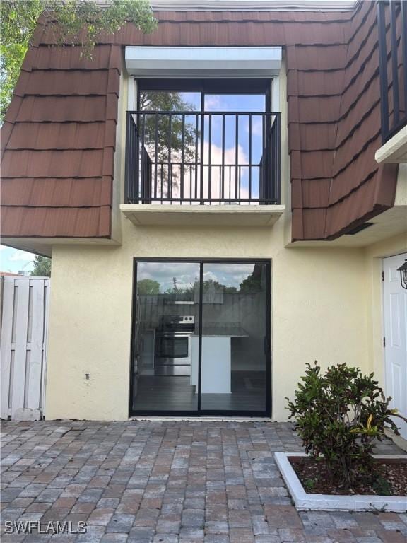 5245 Cedarbend Dr Unit 4, Fort Myers, FL 33919 - back of house with stucco siding, mansard roof, and a balcony
