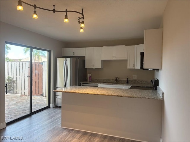5245 Cedarbend Dr Unit 4, Fort Myers, FL 33919 - kitchen with stove, a peninsula, light stone counters, freestanding refrigerator, and white cabinetry
