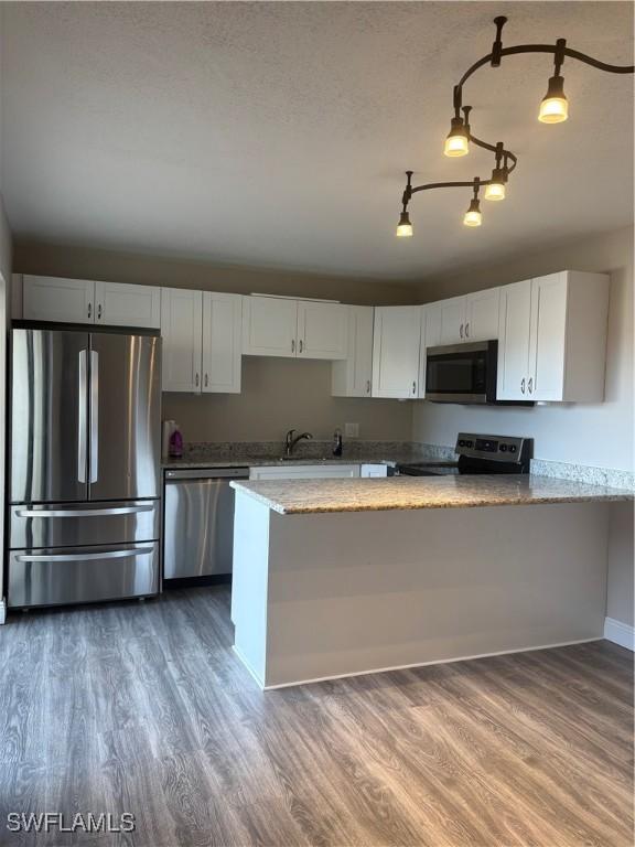 5245 Cedarbend Dr Unit 4, Fort Myers, FL 33919 - kitchen with stainless steel appliances, wood finished floors, light stone counters, and white cabinets