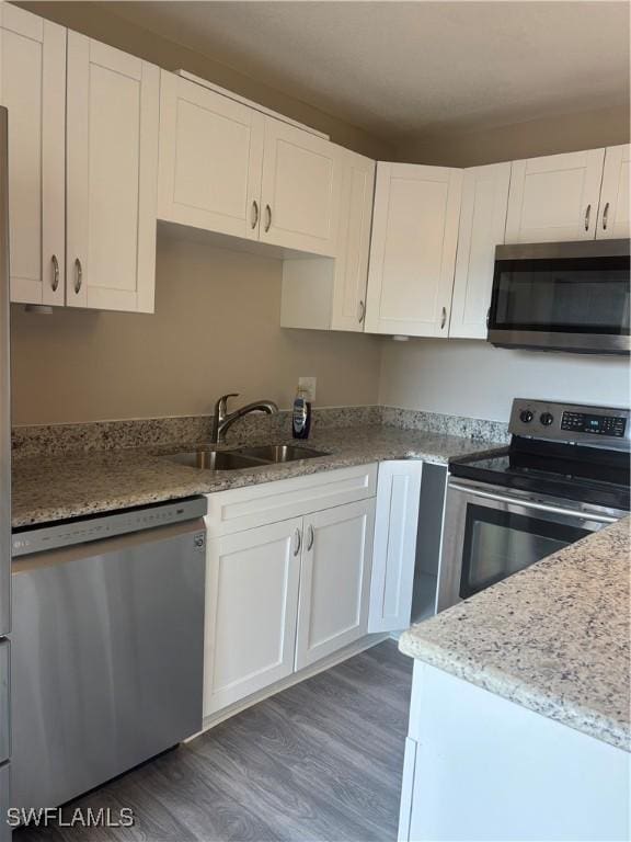 5245 Cedarbend Dr Unit 4, Fort Myers, FL 33919 - kitchen with stainless steel appliances, wood finished floors, white cabinetry, and light stone counters