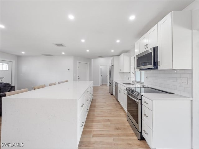505 Monterey Ave, Cape Coral, FL 33904 - kitchen with appliances with stainless steel finishes, a center island, recessed lighting, light wood finished floors, and light countertops