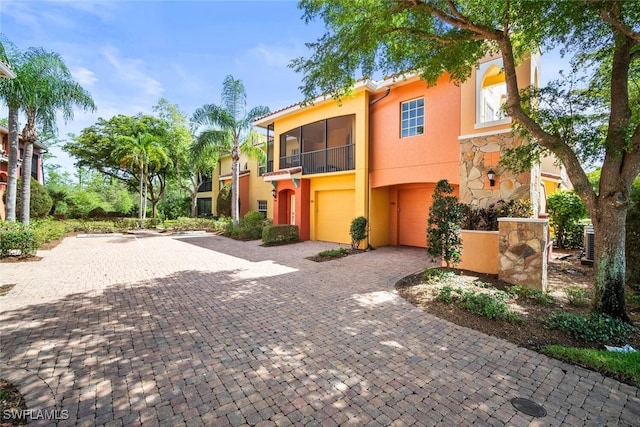8701 Piazza Del Lago Cir Unit 101, Estero, FL 33928 - view of front of property with stucco siding, a balcony, an attached garage, driveway, and stone siding