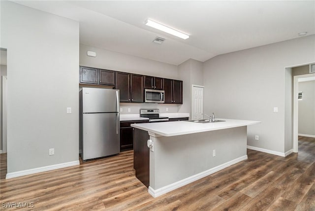 159 Kirby St, Port Charlotte, FL 33954 - kitchen featuring stainless steel appliances, wood finished floors, vaulted ceiling, dark brown cabinetry, and light countertops
