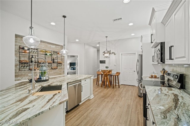 8608 Via Rapallo Dr Unit 206, Estero, FL 33928 - kitchen with appliances with stainless steel finishes, decorative backsplash, white cabinetry, light wood finished floors, and recessed lighting