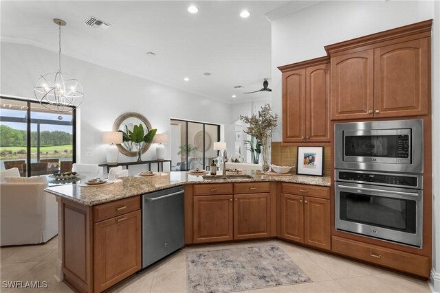 8888 Savona Ct, Naples, FL 34119 - kitchen with appliances with stainless steel finishes, a peninsula, a chandelier, light stone countertops, and brown cabinets