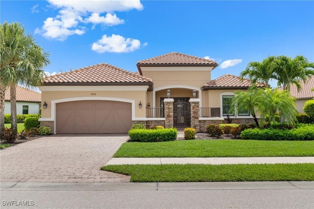 8888 Savona Ct, Naples, FL 34119 - mediterranean / spanish home with stone siding, stucco siding, an attached garage, decorative driveway, and a front yard