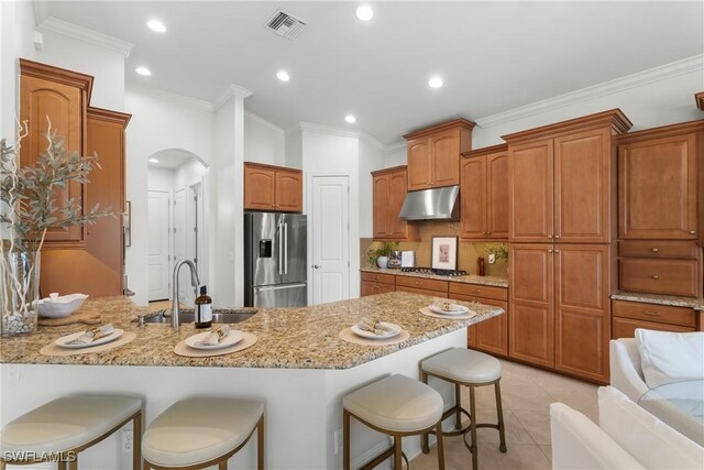 8888 Savona Ct, Naples, FL 34119 - kitchen featuring stainless steel appliances, under cabinet range hood, a breakfast bar, a peninsula, and light stone countertops