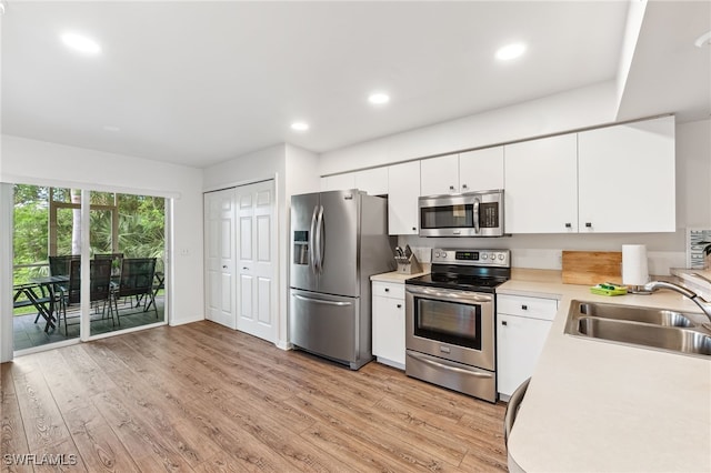 4940 Cougar Ct S Unit 104, Naples, FL 34109 - kitchen with appliances with stainless steel finishes, light countertops, light wood-type flooring, white cabinets, and recessed lighting