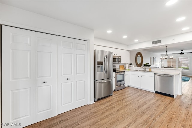 4940 Cougar Ct S Unit 104, Naples, FL 34109 - kitchen with stainless steel appliances, a peninsula, light wood-style flooring, white cabinetry, and recessed lighting