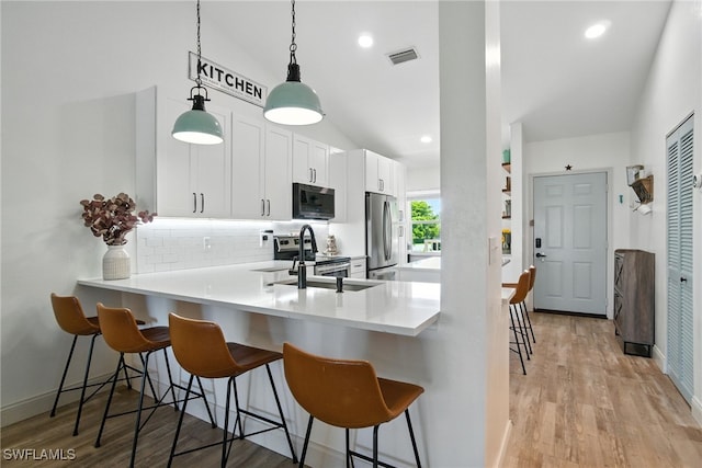 162 Pebble Shores Dr Unit 203, Naples, FL 34110 - kitchen with stainless steel appliances, tasteful backsplash, lofted ceiling, a kitchen breakfast bar, and white cabinetry