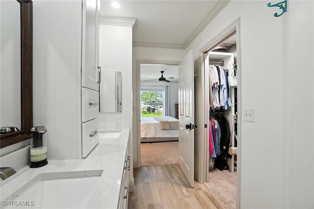 162 Pebble Shores Dr Unit 203, Naples, FL 34110 - ensuite bathroom featuring crown molding, double vanity, wood finished floors, ceiling fan, and a walk in closet