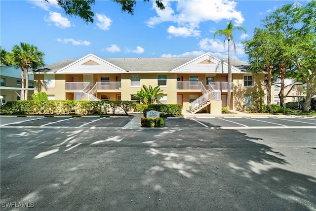 162 Pebble Shores Dr Unit 203, Naples, FL 34110 - view of building exterior featuring stairs and uncovered parking