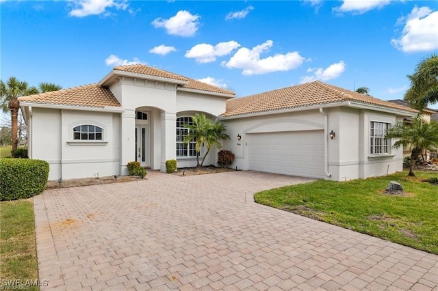 16409 Coco Hammock Way, Fort Myers, FL 34135 - mediterranean / spanish house featuring a tiled roof, a garage, stucco siding, decorative driveway, and a front lawn