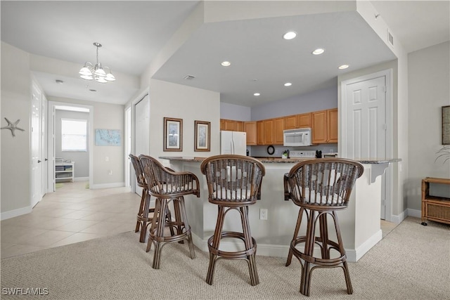 3724 Agualinda Blvd Unit 201, Cape Coral, FL 33914 - kitchen featuring white appliances, recessed lighting, a breakfast bar, light colored carpet, and a chandelier