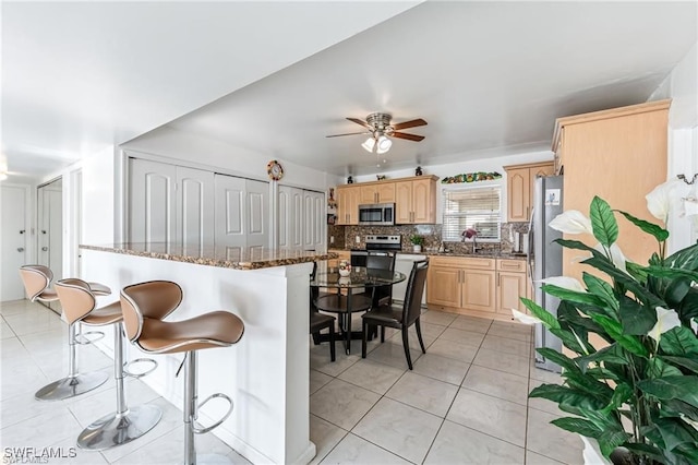 2200 50th St SW, Naples, FL 34116 - kitchen with stainless steel appliances, light brown cabinets, light tile patterned flooring, a kitchen breakfast bar, and ceiling fan