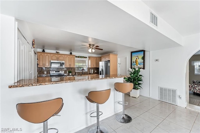 2200 50th St SW, Naples, FL 34116 - kitchen with appliances with stainless steel finishes, arched walkways, a kitchen bar, backsplash, and dark stone countertops