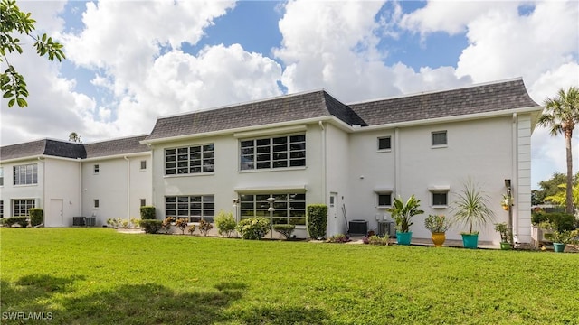 6884 Sandtrap Dr Unit 4, Fort Myers, FL 33919 - back of property with stucco siding, a lawn, mansard roof, and roof with shingles