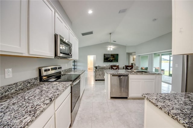 506 NE 2nd Place, Cape Coral, FL 33909 - kitchen featuring appliances with stainless steel finishes, open floor plan, lofted ceiling, white cabinetry, and light stone countertops