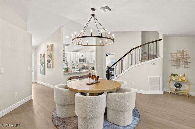 211 11th St NW, Naples, FL 34120 - dining room featuring light wood finished floors, a chandelier, stairs, and high vaulted ceiling