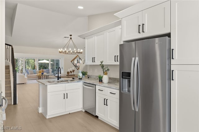 211 11th St NW, Naples, FL 34120 - kitchen featuring stainless steel appliances, open floor plan, a peninsula, white cabinets, and a chandelier