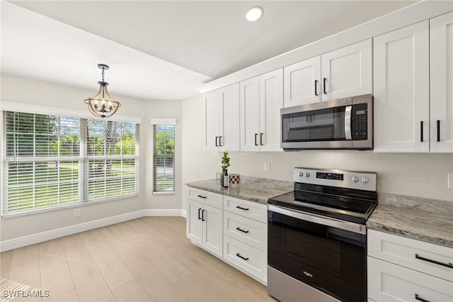 211 11th St NW, Naples, FL 34120 - kitchen with stainless steel appliances, lofted ceiling, white cabinetry, pendant lighting, and light stone counters