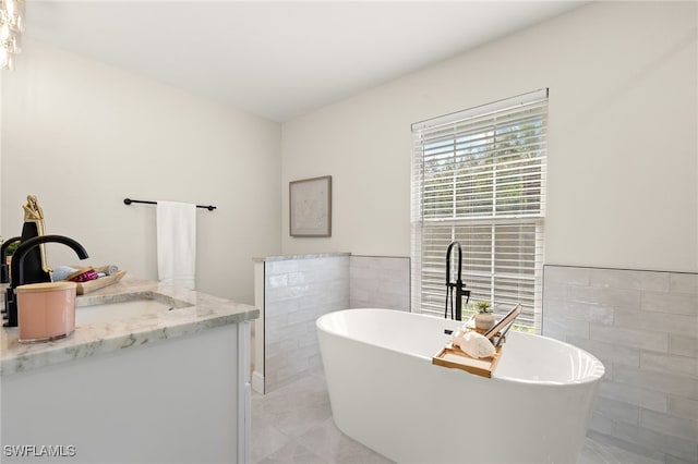 211 11th St NW, Naples, FL 34120 - bathroom with tile walls, a freestanding bath, vanity, marble finish flooring, and wainscoting