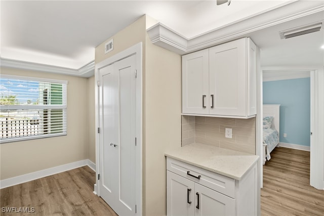 3067 W Gulf Dr Unit 102, Sanibel, FL 33957 - kitchen with light wood-style flooring, decorative backsplash, white cabinetry, and light stone counters