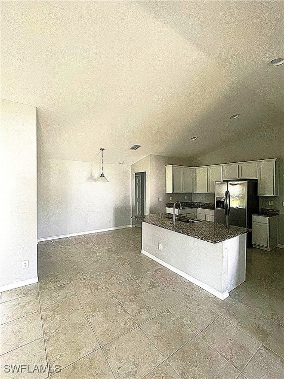 2614 NE 6th Pl, Cape Coral, FL 33909 - kitchen featuring stainless steel fridge, white cabinetry, dark stone counters, a center island with sink, and tile patterned floors