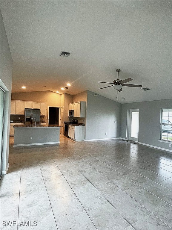 2614 NE 6th Pl, Cape Coral, FL 33909 - unfurnished living room featuring light tile patterned floors, ceiling fan, lofted ceiling, and a textured ceiling