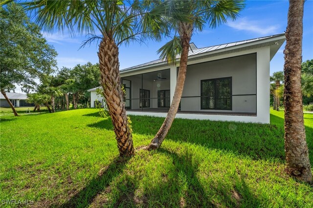 3708 Stagg Ct, Fort Myers, FL 33905 - rear view of house featuring stucco siding, a yard, a standing seam roof, a sunroom, and a ceiling fan