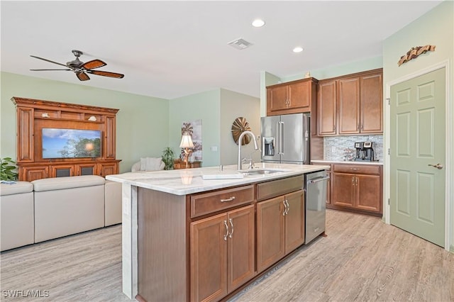 3344 Apple Blossom Dr, Alva, FL 33920 - kitchen with appliances with stainless steel finishes, light wood-style floors, a ceiling fan, an island with sink, and decorative backsplash